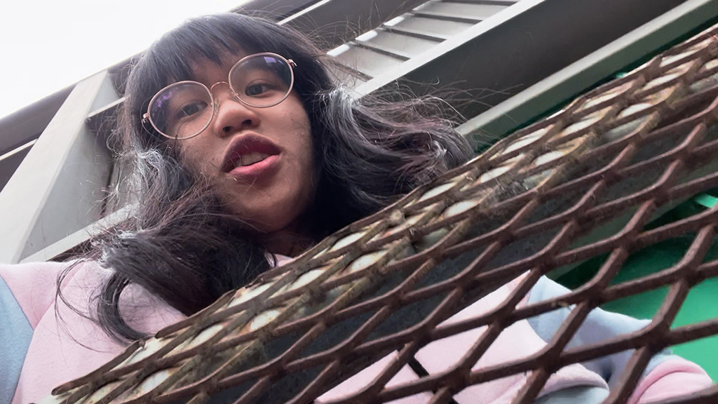 Woman looking down over balcony with metal fencing