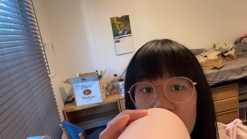 Woman drinking water bottle with box of vodka in background