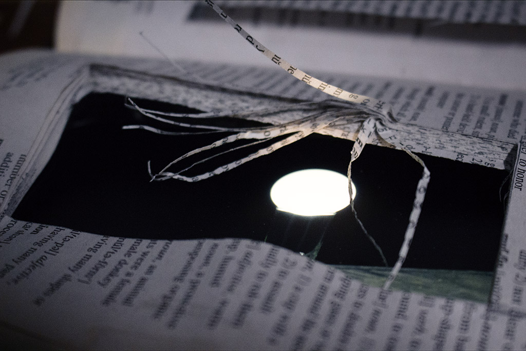 Inside a book, a screen displays a glowing orb