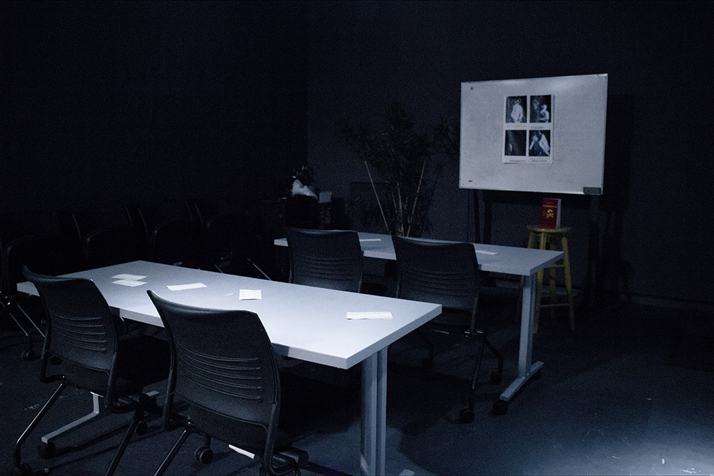 A dimly lit classroom with propaganda posters on the whiteboard